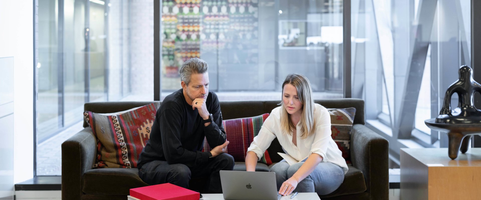 man en vrouw achter de computer in een ruim kantoor